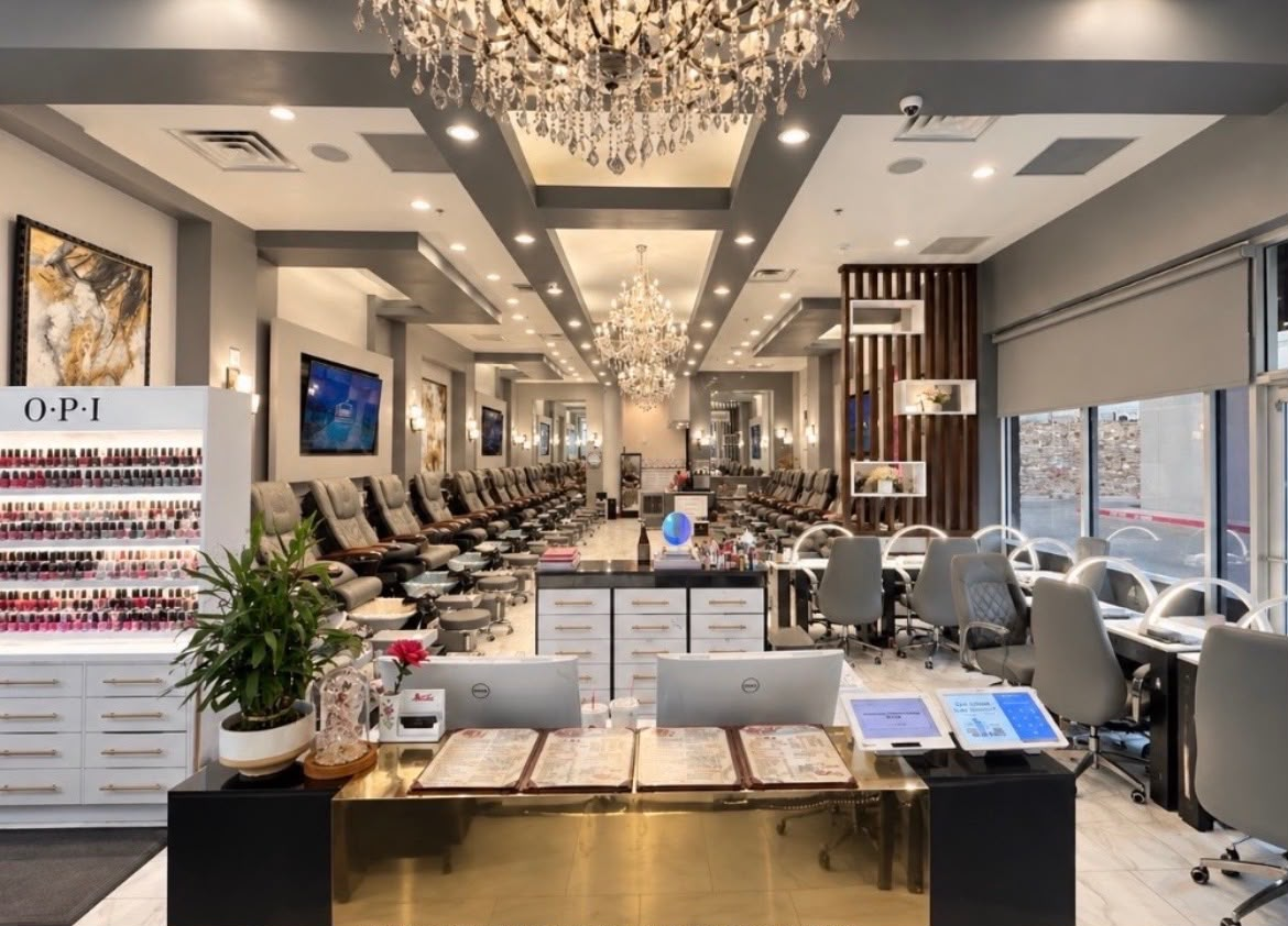 Deluxe Nails Salon interior seen from the gold reception desk, with crystal chandeliers and rows of pedicure chairs